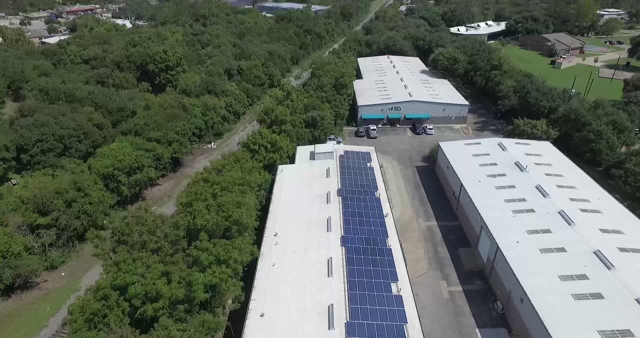 Aerial over a Texas commercial rooftop solar array at golden hour.