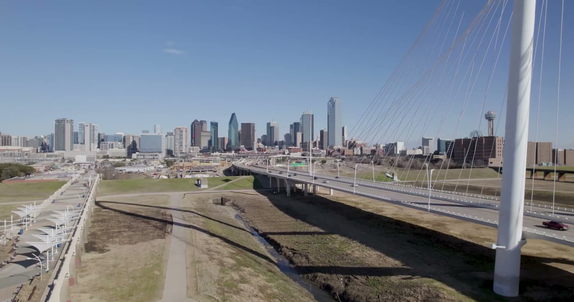 Calm wide aerial of a Texas skyline and bridge at golden hour.