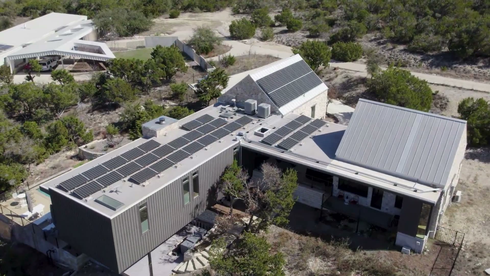 A custom Texas Hill Country home with a rooftop solar array at golden hour.