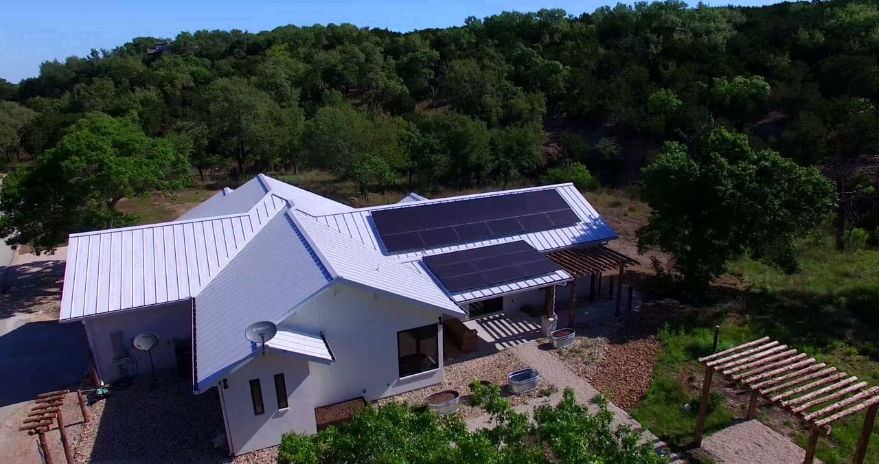 Aerial orbit of a Texas Hill Country home with rooftop solar.